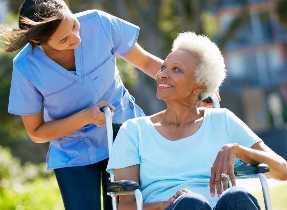 Caregiver pushing elderly in wheelchair