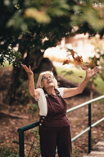 Elderly woman tossing leaves in the air